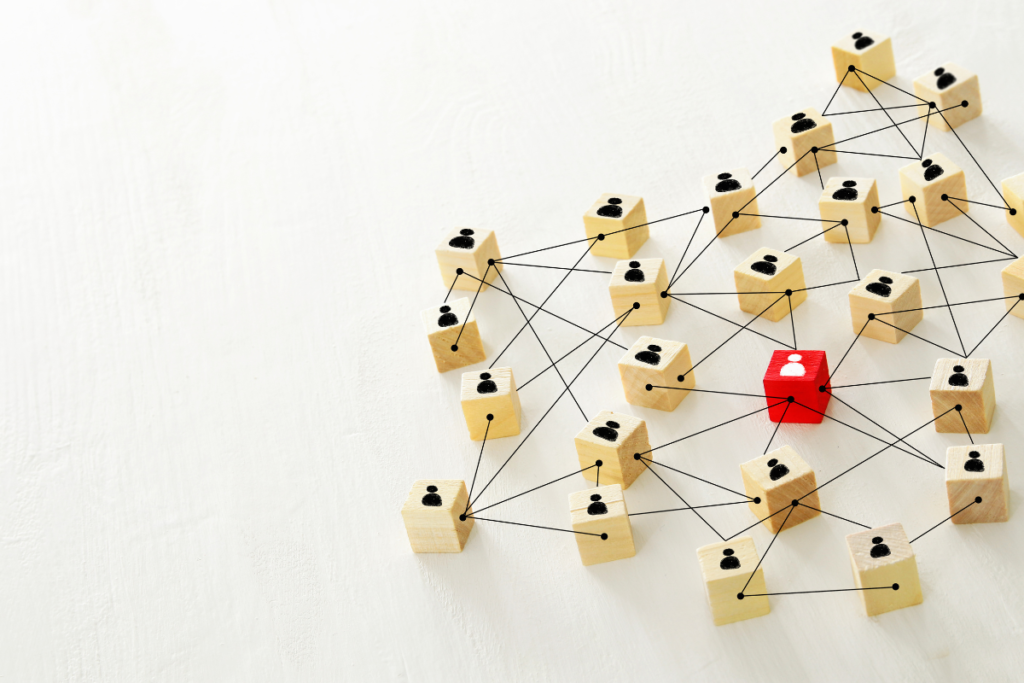 Wooden blocks with human icons connected by lines, with one red block at the center, symbolizing LinkedIn outreach and professional networking.